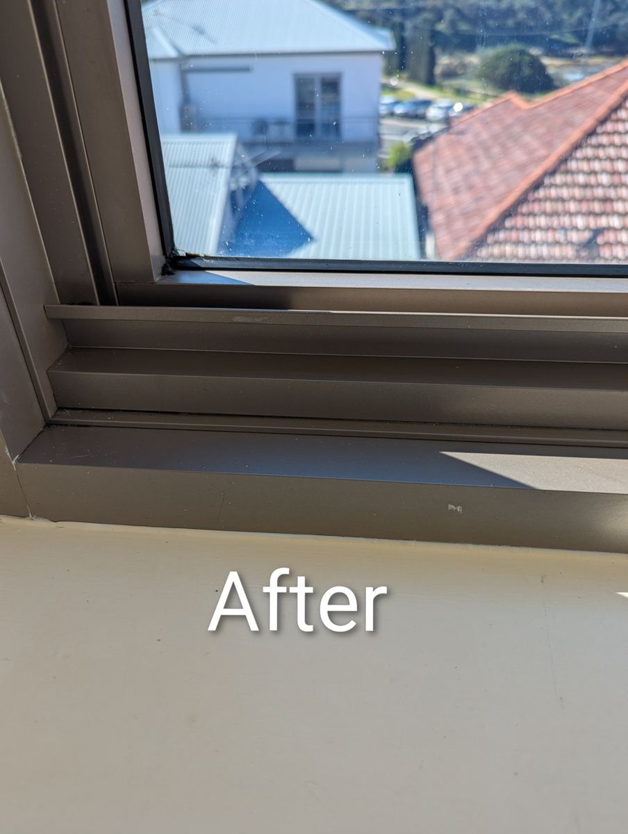 The same window sill and tracks wiped clean, with clear glass