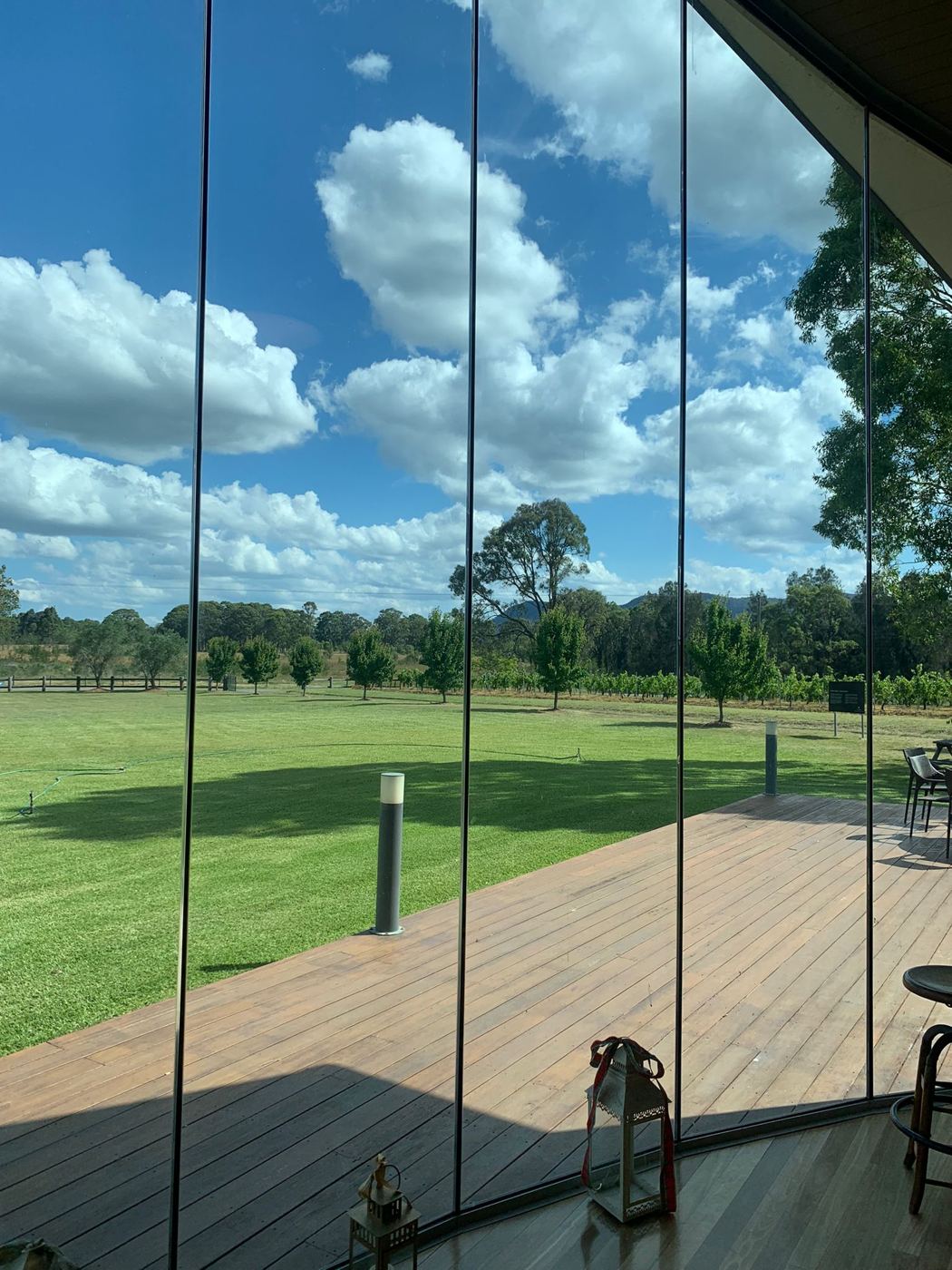 Floor-to-ceiling glass wall looking out over a lawn and deck, perfectly clear