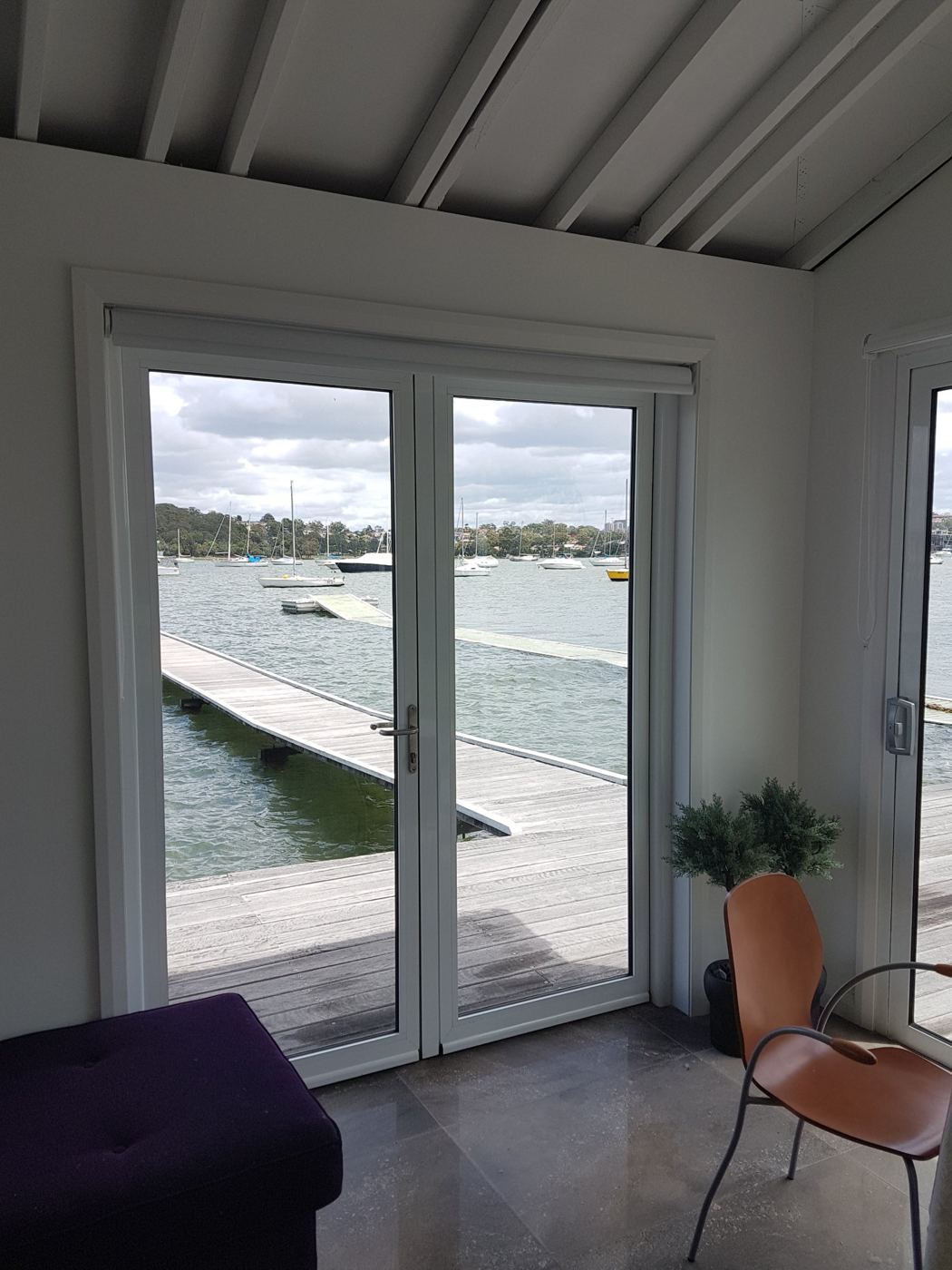 Clean French doors looking out to a jetty and moored boats