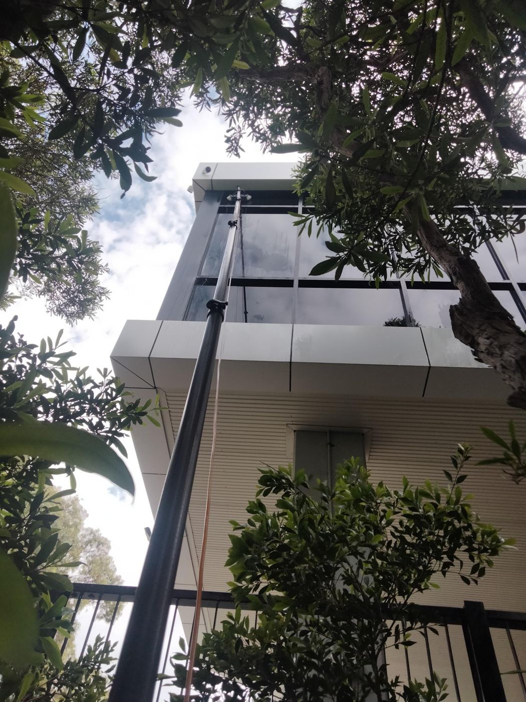 Water-fed pole reaching the upper windows of a multi-storey building